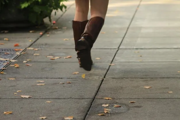 A close-up of a person's legs and feet as they walk briskly on a paved road. The focus is on the motion and the ground beneath, showcasing the physical effort involved in walking. The scene suggests active movement and outdoor exercise.