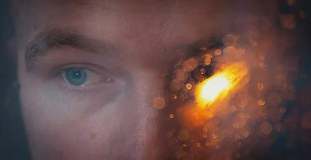 Close-up of a digital screen emitting blue light, with a person's eye reflecting the light. The eye looks slightly strained and tired.