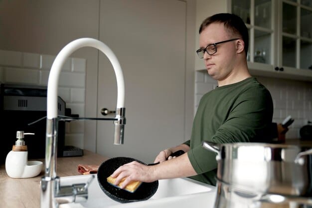 A person mindfully washing dishes at their kitchen sink, focusing on the warm water and the feel of the soap on their hands. The kitchen is clean and bright, and the person appears relaxed and focused on the task at hand.