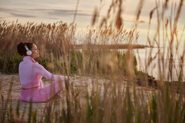 A person practicing deep breathing exercises in a serene natural setting. The sun is setting, casting a warm, golden light on the scene. The individual appears calm and focused, with their eyes closed and hands resting gently on their knees.