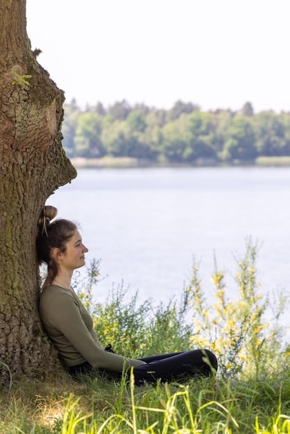 A person meditating in a peaceful setting, with sunlight filtering through the trees. Their eyes are closed, and they have a serene expression on their face, symbolizing self-compassion and inner peace.