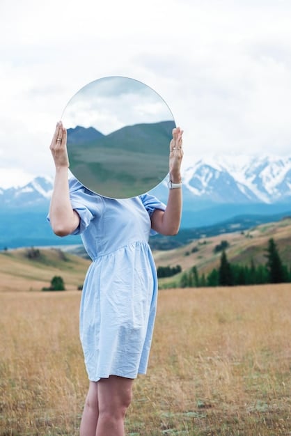 A close-up of a person's hands gently holding a mirror reflecting their own face, symbolizing the act of self-reflection and self-forgiveness, with a soft focus to convey gentleness and compassion.