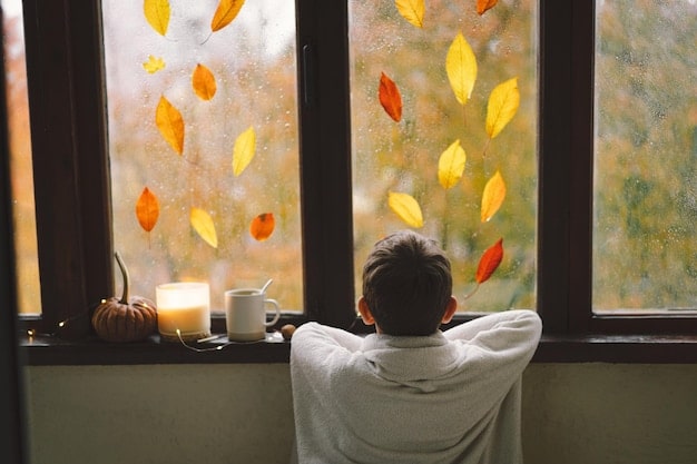 A person looking out a rain-streaked window, but smiling despite the gloomy weather, symbolizing finding gratitude even in challenging circumstances.