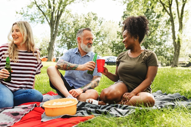 A group of diverse friends laughing and talking while having a picnic in a sunny park, highlighting connection and joy.