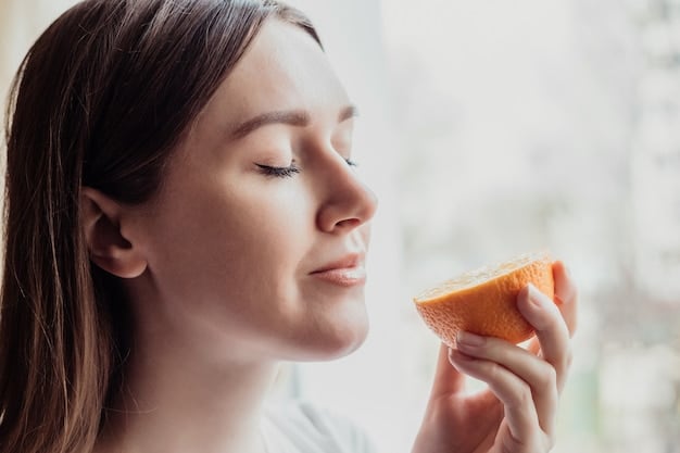 A close-up shot of someone mindfully smelling a slice of orange before eating it, eyes closed, with soft focus on the background.