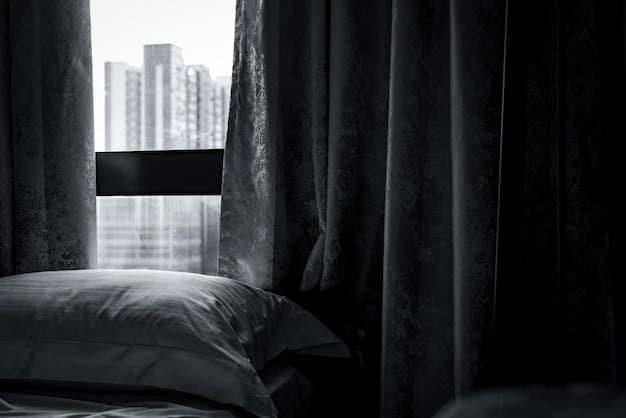 A dark and quiet bedroom setup with blackout curtains, a comfortable bed, and a white noise machine on a nightstand.