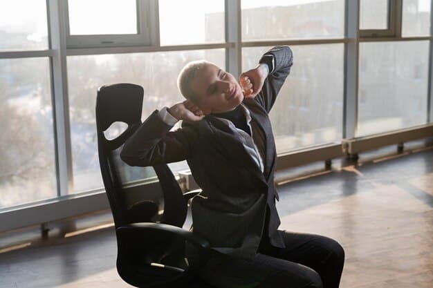 A person sitting in an office chair, performing a neck roll by tilting their head gently to the side. The background shows a typical office environment.